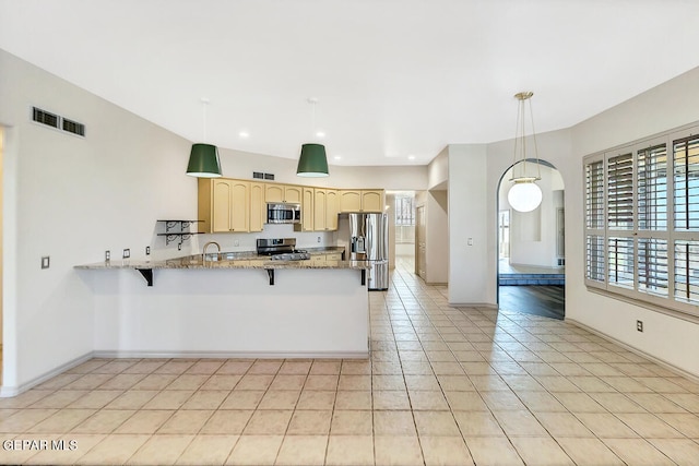 kitchen featuring pendant lighting, light tile patterned flooring, kitchen peninsula, stainless steel appliances, and light stone countertops