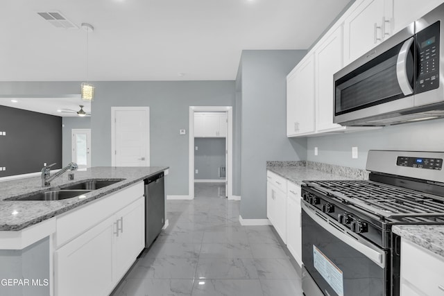 kitchen with stainless steel appliances, sink, white cabinets, and light stone counters