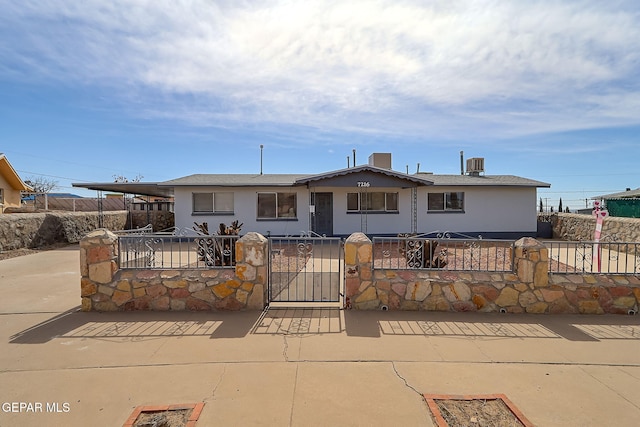 view of front facade featuring central air condition unit, a fenced front yard, a gate, and stucco siding