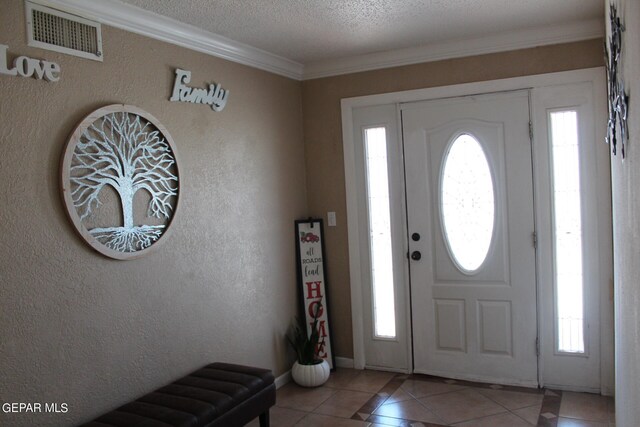 tiled foyer featuring ornamental molding and a textured ceiling