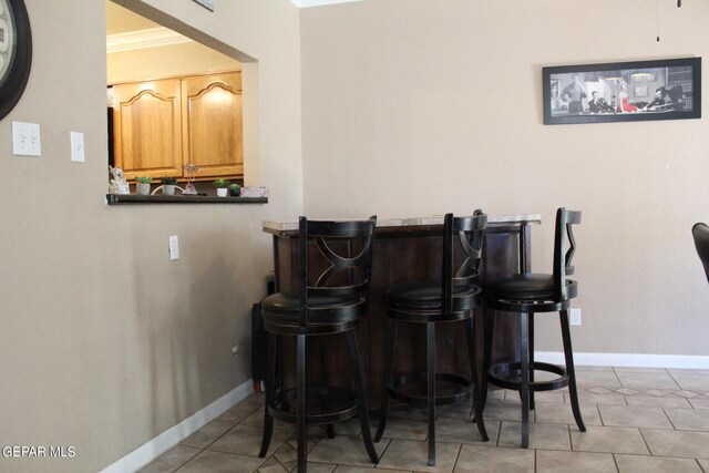 bar with crown molding and light tile patterned floors