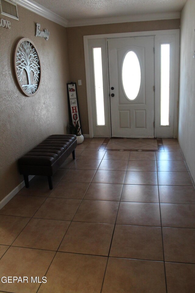 foyer with ornamental molding, tile patterned flooring, and a textured ceiling