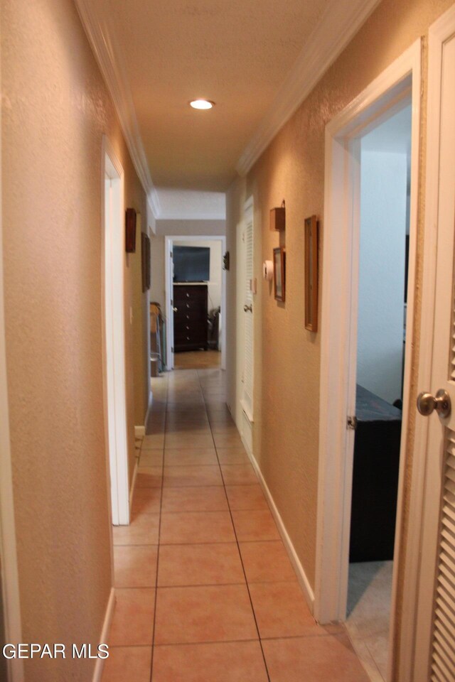 hallway with ornamental molding and light tile patterned floors