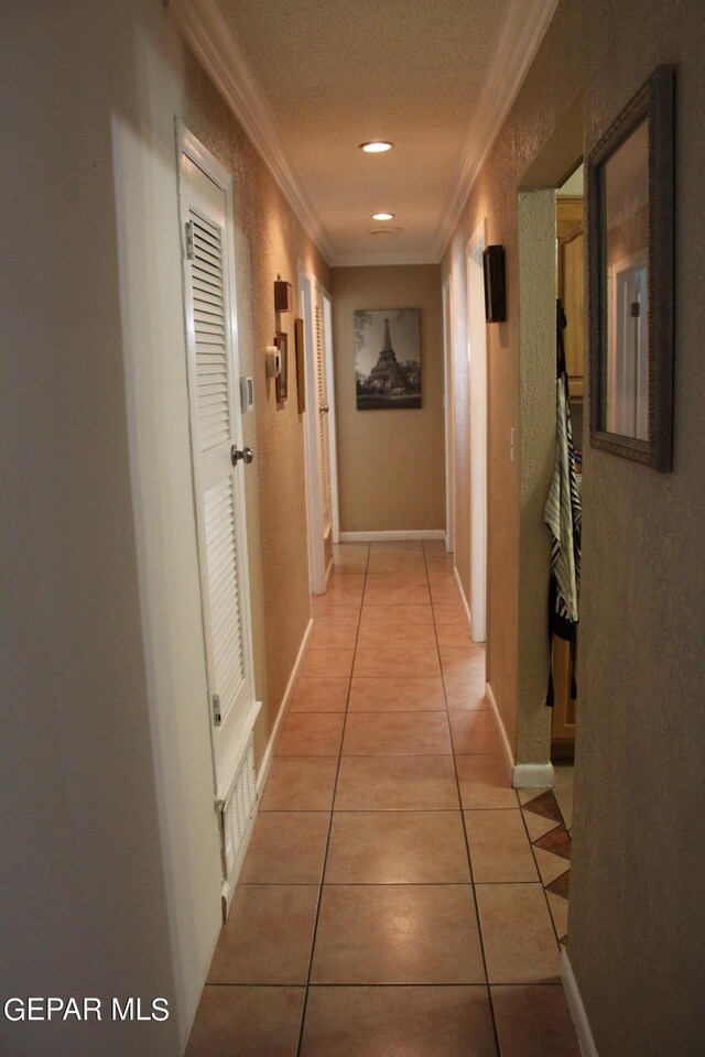 hallway with crown molding, a textured ceiling, and light tile patterned floors