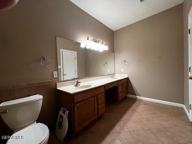 bathroom featuring tile patterned floors, vanity, toilet, and tile walls