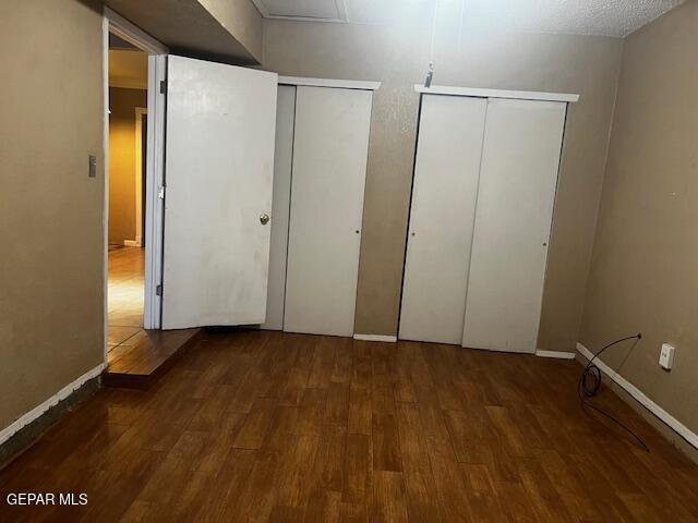 unfurnished bedroom featuring dark hardwood / wood-style floors and two closets