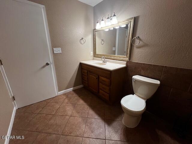 bathroom featuring vanity, tile patterned floors, tile walls, and toilet