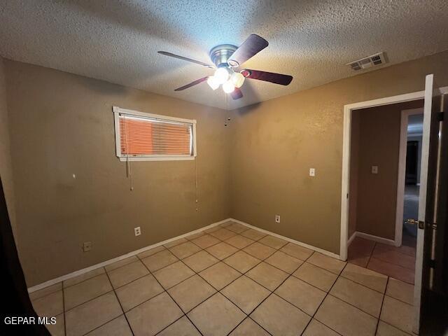 tiled spare room featuring a textured ceiling and ceiling fan