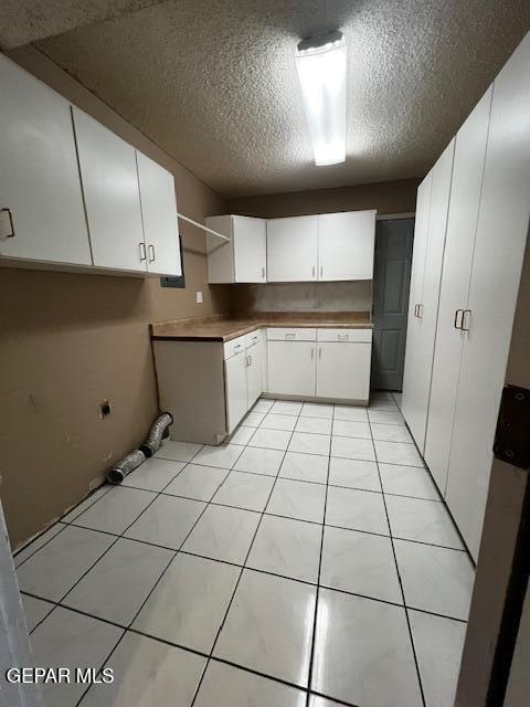 kitchen featuring white cabinetry, light tile patterned flooring, and a textured ceiling