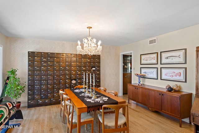 dining room with a mail area, light hardwood / wood-style flooring, and a notable chandelier