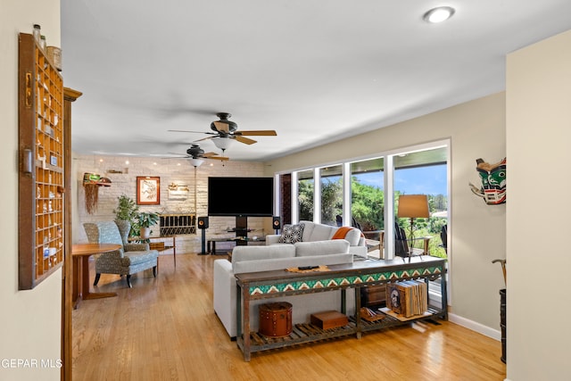 living room featuring ceiling fan, light hardwood / wood-style flooring, and brick wall