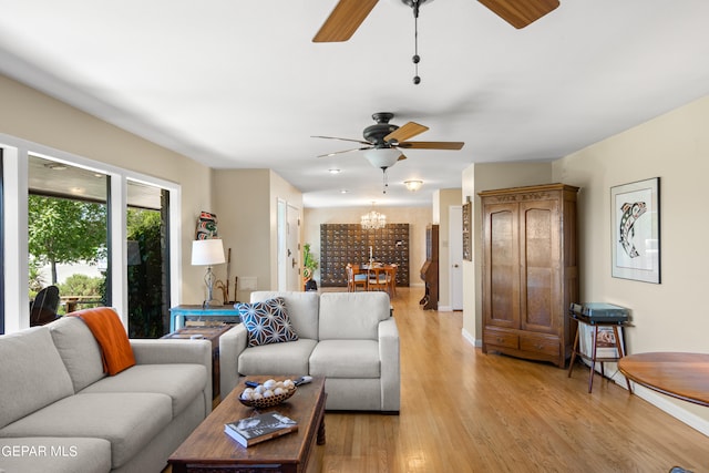 living room featuring ceiling fan with notable chandelier and light hardwood / wood-style floors