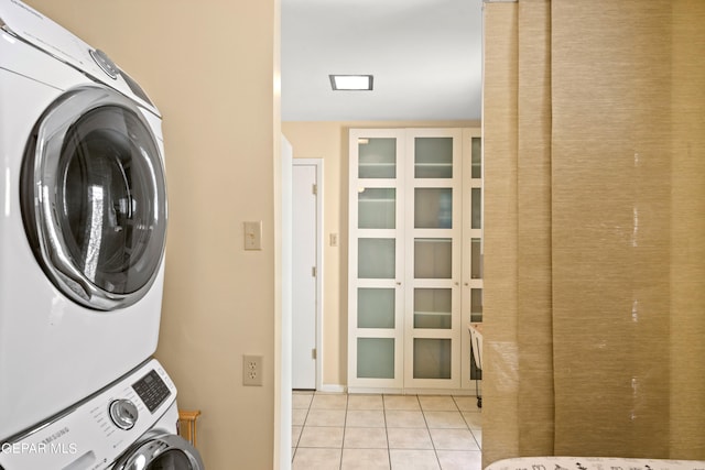 laundry area featuring light tile patterned floors and stacked washing maching and dryer