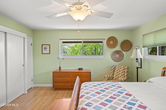 bedroom featuring ceiling fan, a closet, light hardwood / wood-style floors, and multiple windows