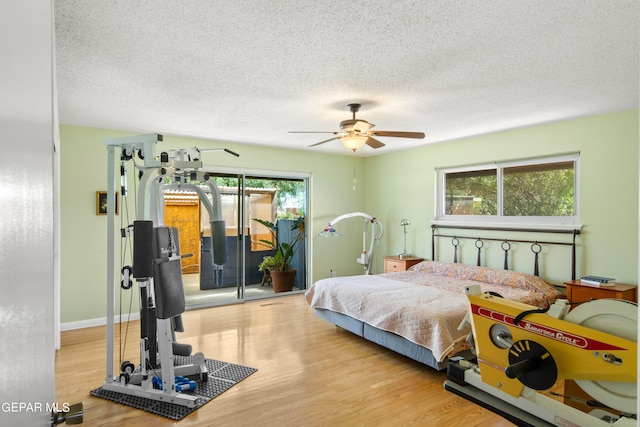 bedroom with light hardwood / wood-style flooring, ceiling fan, access to exterior, and a textured ceiling