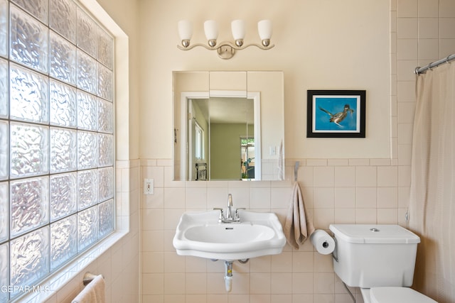 bathroom with curtained shower, tile walls, toilet, and sink