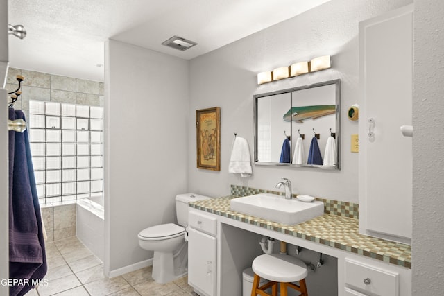 bathroom with tiled bath, vanity, a textured ceiling, tile patterned flooring, and toilet