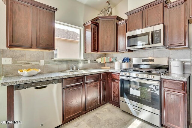 kitchen with backsplash, appliances with stainless steel finishes, light stone counters, and sink