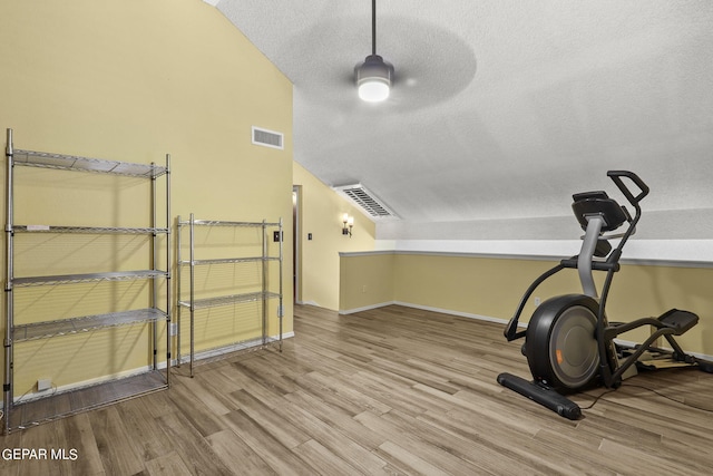 workout room with a textured ceiling, lofted ceiling, ceiling fan, and light hardwood / wood-style flooring