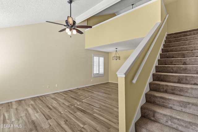 stairway featuring high vaulted ceiling, wood-type flooring, ceiling fan, and a textured ceiling