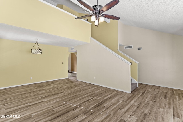 unfurnished living room with ceiling fan, hardwood / wood-style flooring, and a textured ceiling