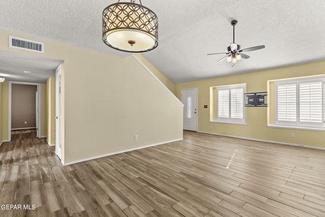 unfurnished living room with ceiling fan, hardwood / wood-style floors, and a textured ceiling