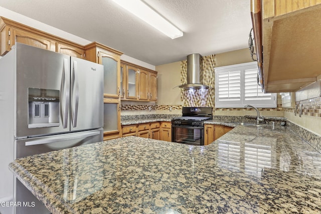 kitchen with kitchen peninsula, sink, stainless steel fridge with ice dispenser, wall chimney range hood, and black range with gas stovetop