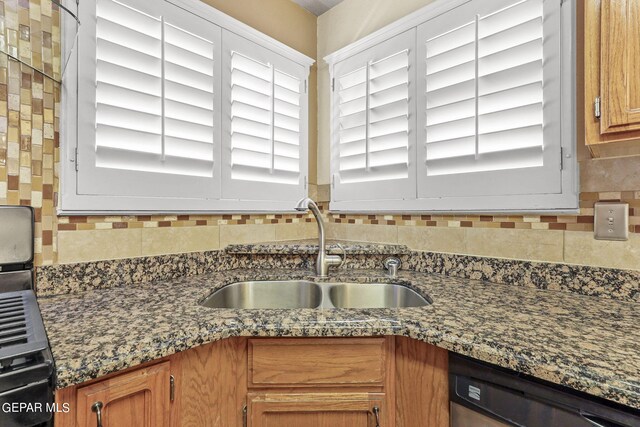 kitchen with dishwasher, dark stone counters, sink, and decorative backsplash