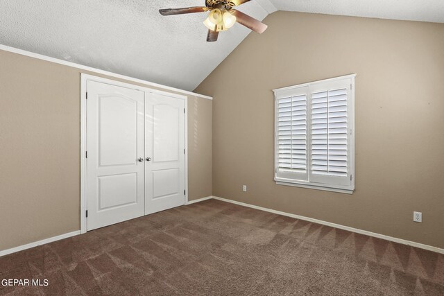 unfurnished bedroom with ceiling fan, a closet, vaulted ceiling, and carpet