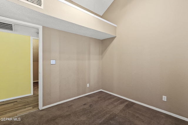 unfurnished room featuring dark carpet and a textured ceiling