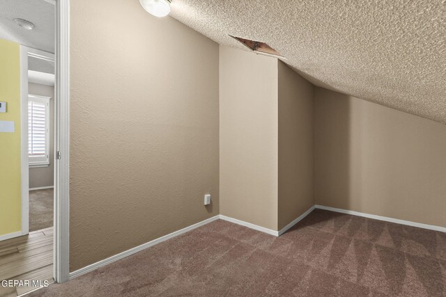 bonus room with carpet floors, a textured ceiling, and lofted ceiling