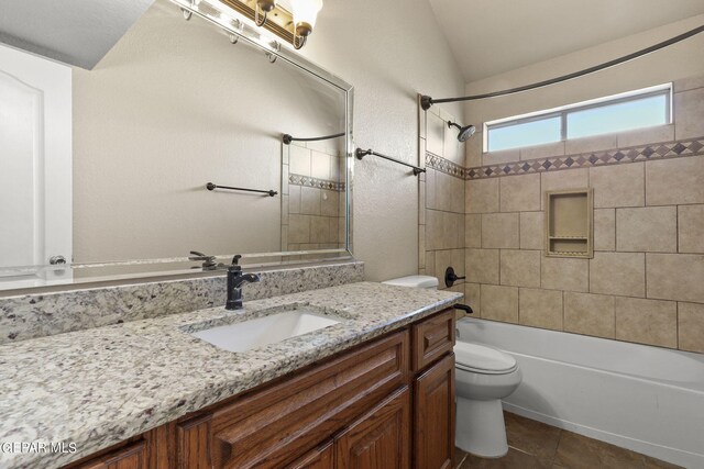 full bathroom with tile patterned flooring, vaulted ceiling, tiled shower / bath combo, vanity, and toilet