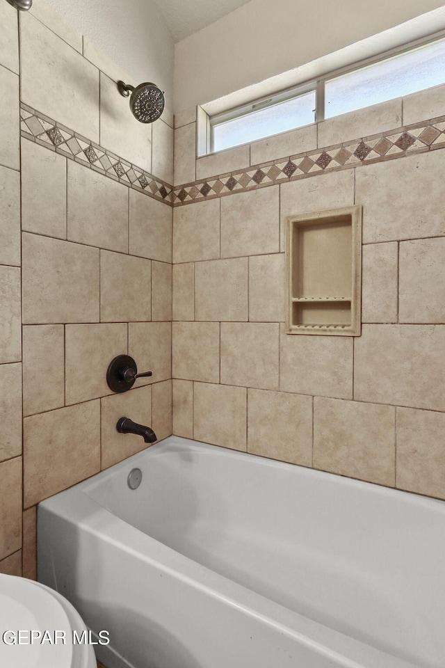 bathroom with tiled shower / bath combo and toilet