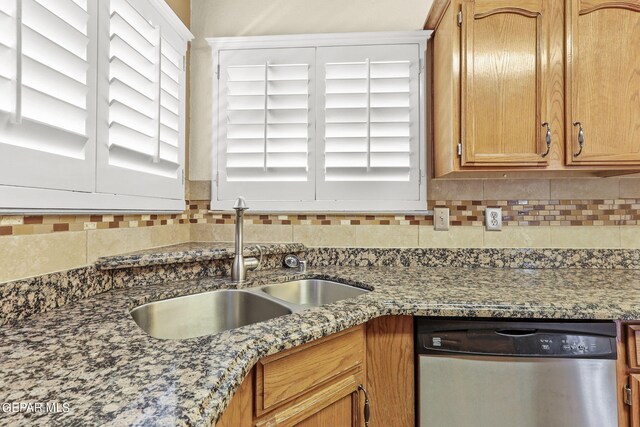 kitchen featuring backsplash, stone counters, dishwasher, and sink