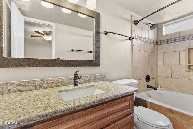 full bathroom featuring vanity, a textured ceiling, tiled shower / bath combo, ceiling fan, and toilet