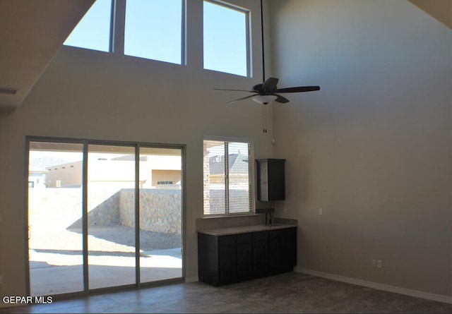 unfurnished living room with high vaulted ceiling, ceiling fan, and a wealth of natural light