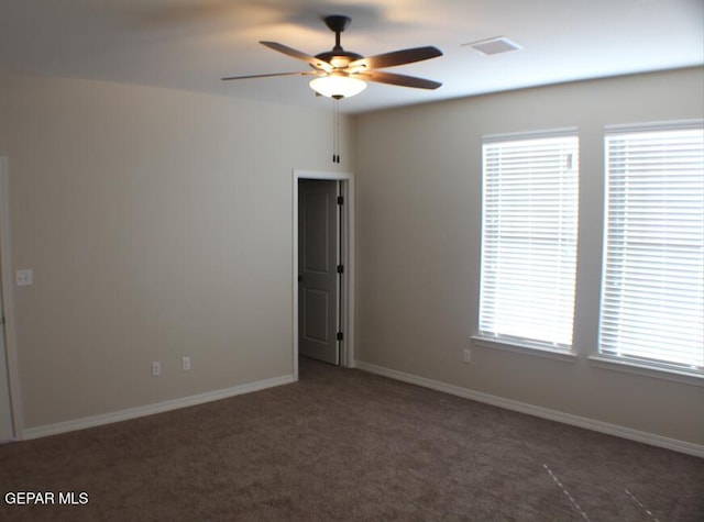 spare room featuring dark colored carpet and ceiling fan