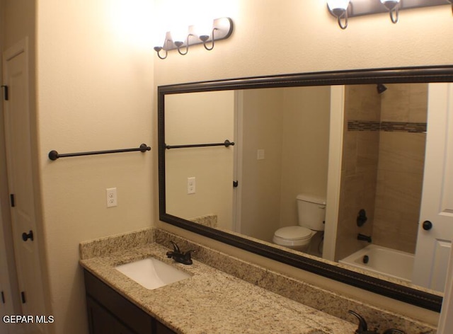 full bathroom with tiled shower / bath, vanity, and toilet