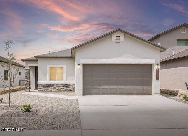 view of front of property with driveway, stone siding, an attached garage, and stucco siding