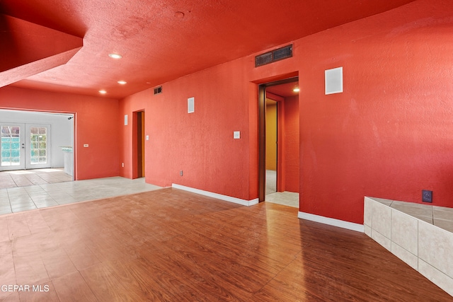 unfurnished room featuring hardwood / wood-style flooring, french doors, and a textured ceiling