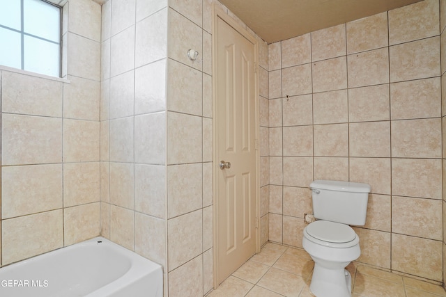 bathroom featuring tile walls, toilet, a washtub, and tile patterned floors