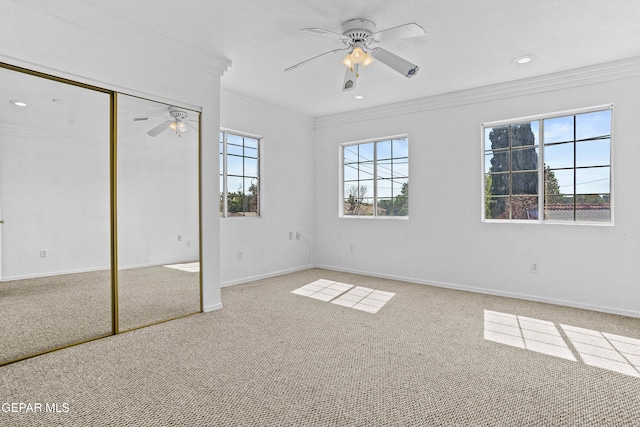 unfurnished bedroom with ornamental molding, ceiling fan, carpet floors, and a closet