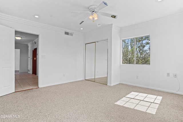 unfurnished bedroom featuring ornamental molding, ceiling fan, a closet, and carpet