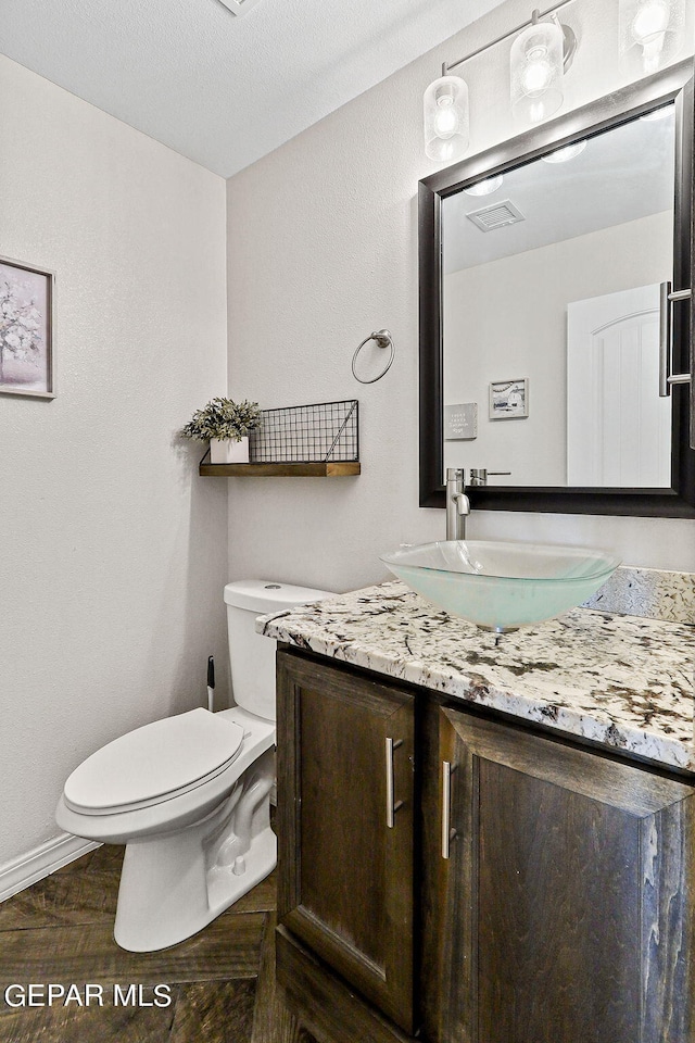 bathroom featuring vanity, a textured ceiling, toilet, and parquet floors