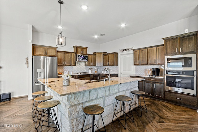 kitchen featuring a breakfast bar, appliances with stainless steel finishes, a spacious island, and dark parquet flooring