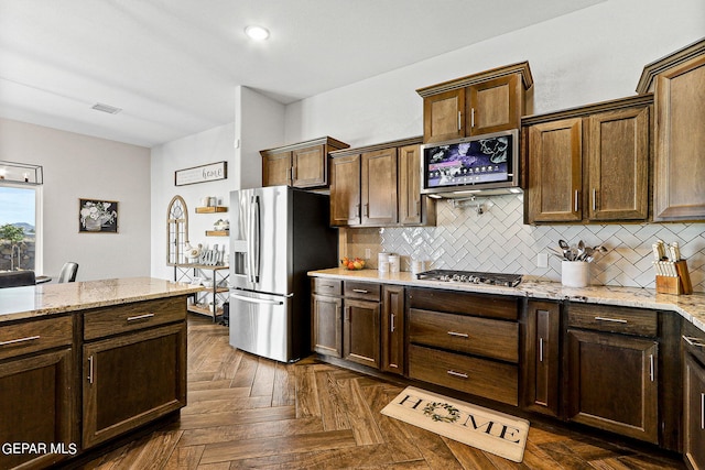 kitchen featuring light stone counters, dark parquet floors, appliances with stainless steel finishes, and backsplash