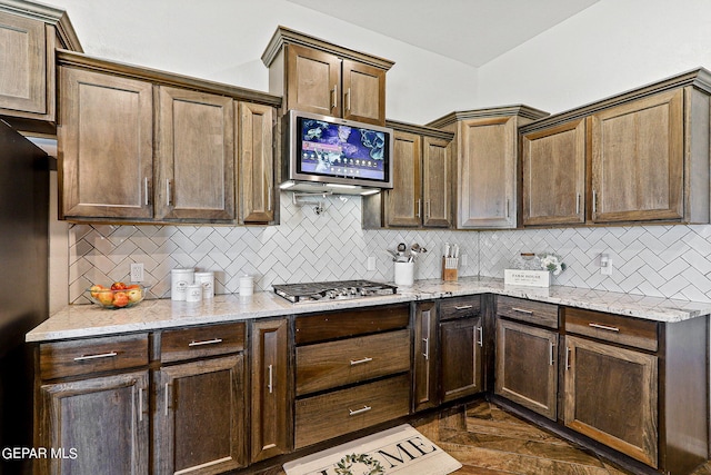 kitchen with stainless steel gas stovetop, light stone countertops, and decorative backsplash