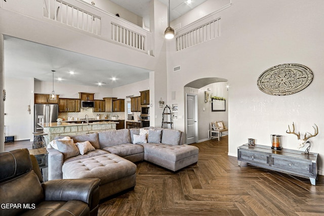 living room with a towering ceiling and dark parquet flooring