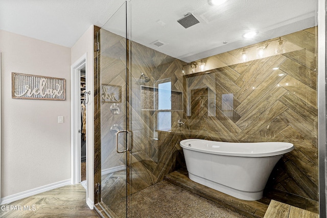 bathroom with a textured ceiling, independent shower and bath, and tile walls