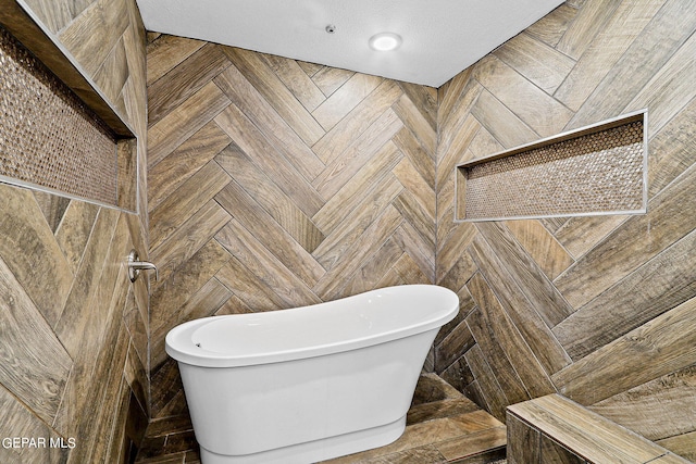 bathroom featuring parquet flooring, a textured ceiling, and a washtub